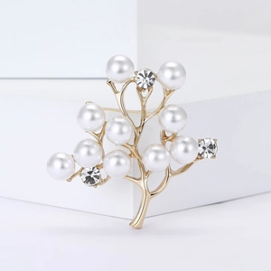 Élégante broche arbre dorée avec perles blanches et cristaux brillants sur support blanc