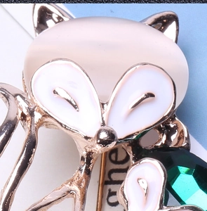 Detailed close-up of a fox brooch with pink opal head and green faceted crystal