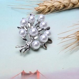 Detail shot of a silver alloy bouquet brooch with white imitation pearls on a textured background