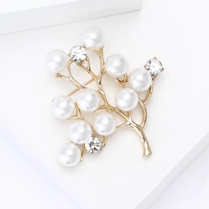 Détails d'une élégante broche branche dorée avec perles et cristaux brillants