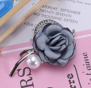 Detail of fabric rose brooch with grey-blue petals, white pearl and sparkling rhinestones