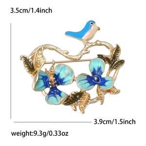 Elegant gold branch brooch with blue enamel flowers and a bird on a white background