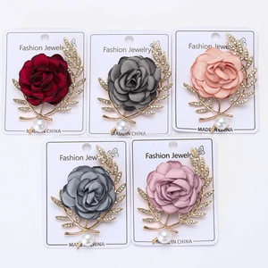 Détail de broches roses en tissu avec feuilles en strass et perles en cinq couleurs