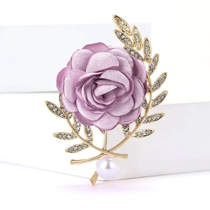 Vue détaillée d'une broche rose en tissu violet avec feuilles dorées et perle