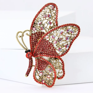 Close-up of golden butterfly brooch with sparkling red rhinestones and hollow patterns