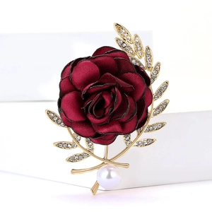 Détail de la broche rose en tissu bordeaux avec feuilles dorées et perle blanche