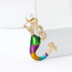 Golden mermaid brooch with colorful enamel tail and pearl accent on stone backdrop