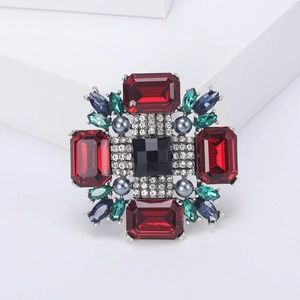 Détail macro de broche rétro avec gemmes rouges carrées et accents émeraude