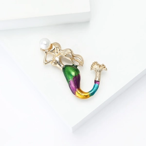 Elegant gold mermaid brooch with colorful enamel gradient and a pearl on a white pedestal