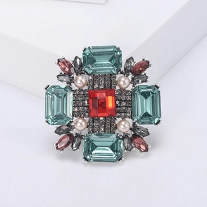 Détail d'une broche fleur vintage avec pierre carrée rouge et gemmes taille émeraude