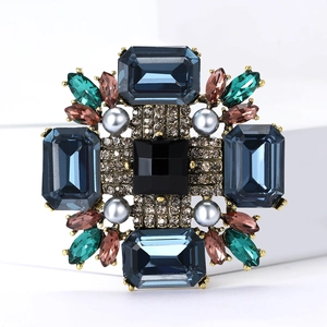 Broche vintage dorée avec cristal noir, pierres bleues et perles grises sur fond blanc