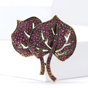 Close-up of vintage gold leaf brooch with purple rhinestones on white display stand