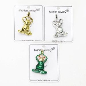Macro detail of three vintage yoga frog brooches in gold, silver, and green enamel