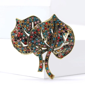 Macro view of crystal encrusted ginkgo leaf brooch with vintage gold finish