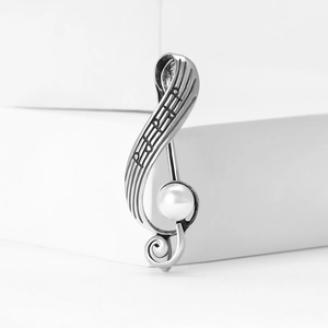 Vintage silver musical note brooch featuring a treble clef design with a white round pearl