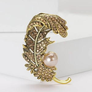 Broche plume dorée élégante avec cristaux ambre et perle rose sur support en pierre