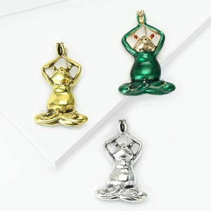 Retro yoga frog brooches in antique gold, silver, and green enamel on a display stand