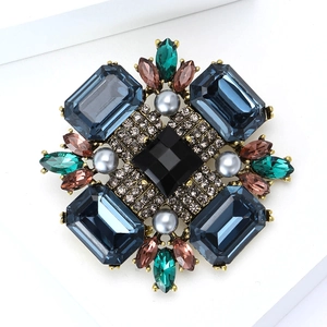 Détail macro d'une broche vintage avec cristaux bleus carrés et accents de perles baroques