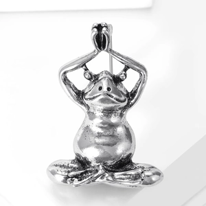 Detailed macro shot of vintage silver frog brooch in yoga pose with antique finish