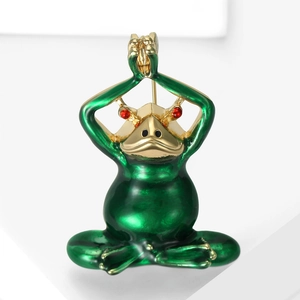 Detailed macro shot of a green enamel yoga frog brooch with red rhinestone eyes