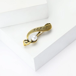 Detailed view of vintage gold musical note brooch featuring a white faux pearl and textures