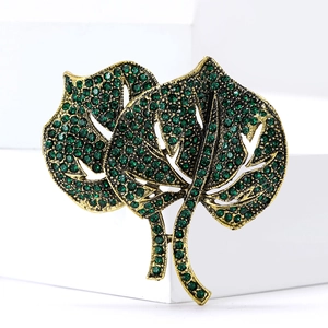 Macro detail of leaf brooch with green crystals and vintage gold finish