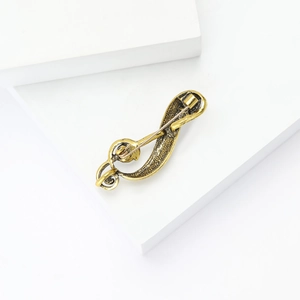 Close-up of vintage treble clef brooch back showing the long pin fastener and texture