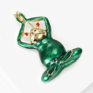 Detailed close-up of a green enamel yoga frog brooch with gold accents and red stone eyes
