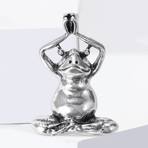 Detail shot of vintage silver yoga frog brooch featuring a meditative pose with oxidized finish