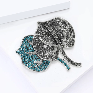 Macro shot of double leaf brooch with gradient blue and grey rhinestones and silver alloy base