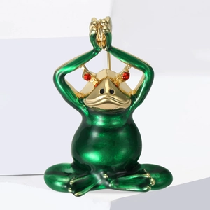 Macro detail of vintage green frog brooch with gold finish and red stone eyes on white stairs