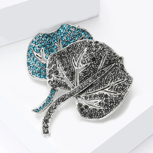 Detailed macro view of silver leaf brooch set with blue and grey rhinestones on a pedestal