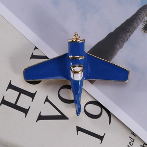 Detailed macro view of an enamel airplane brooch with blue finish and gold metal trim