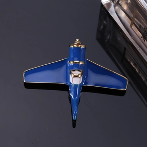 Detailed view of navy blue enamel airplane brooch with golden metallic edges on dark surface