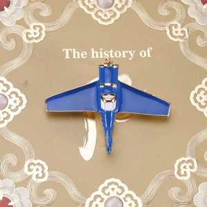 Close-up of blue enamel airplane brooch with gold trim on an elegant textured background