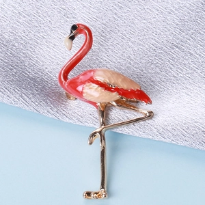 Detailed close-up of flamingo brooch featuring red enamel and golden alloy on metallic cloth
