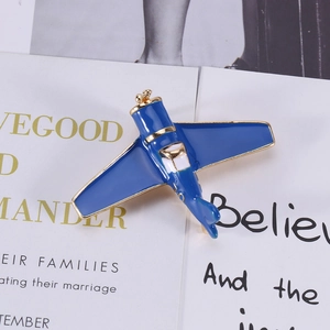 Detail of blue enamel airplane brooch with vintage design and gold-plated metallic edges