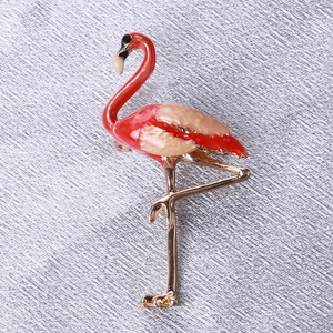Close-up of elegant flamingo enamel brooch with gold-plated details on silk