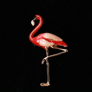 Macro view of gold-plated flamingo brooch with red and cream enamel details on dark base