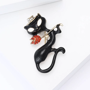 Détail d'une broche chat en émail avec rose en cristal rouge et chapeau en diamant sur socle