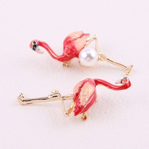 Macro shot of flamingo brooches with enamel gradient and pearl detail on leather