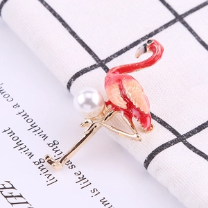 Macro view of flamingo brooch with pink enamel feathers and pearl inlay detail