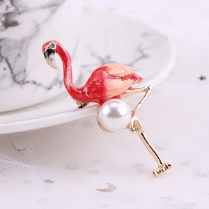 Detail view of enamel flamingo brooch with pearl inlay on marble background