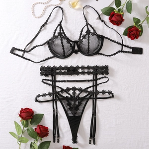 Detailed flat lay of black floral lace lingerie set with red roses and pearls