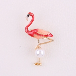 Detailed macro view of an enamel flamingo brooch with gold edges and a white pearl accent