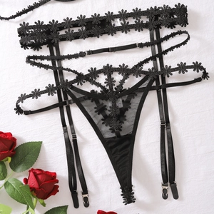 Detail of black lace lingerie with daisy floral embroidery and adjustable garter straps