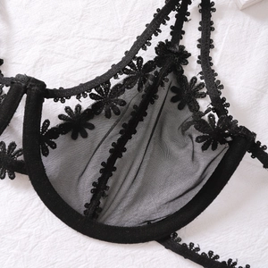 Detail of black mesh lingerie featuring 3D daisy flower embroidery and lace edges