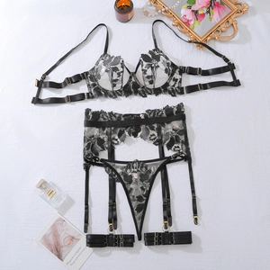 Detail of floral embroidery on four-piece lingerie set with golden metal buckles