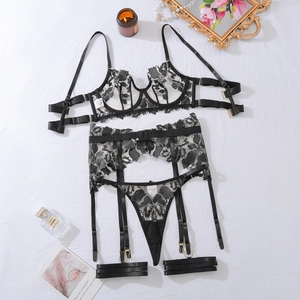 Flat lay of black floral lace lingerie set with garters on white textured background