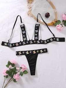 Detailansicht eines schwarzen Lingerie-Sets mit bunten Schmetterlingen und Metallketten